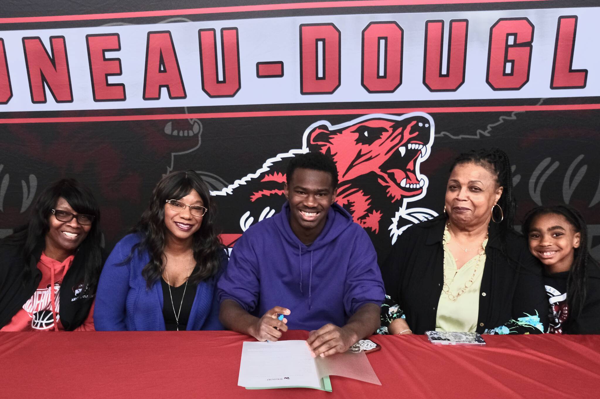 Juneau-Douglas High School: Yadaa.at Kalé senior Ahmir Parker, center, signed a letter of intent Thursday in the JDHS commons to attend Waldorf University in Forest City, Iowa, and play soccer for the Viking Warriors. From left are Parkers maternal grandmother Michelle Monts, mother Kelli Patterson, Ahmir Parker, grandmother Sherry Patterson and little sister Makaylah Patterson. (Klas Stolpe / Juneau Empire)