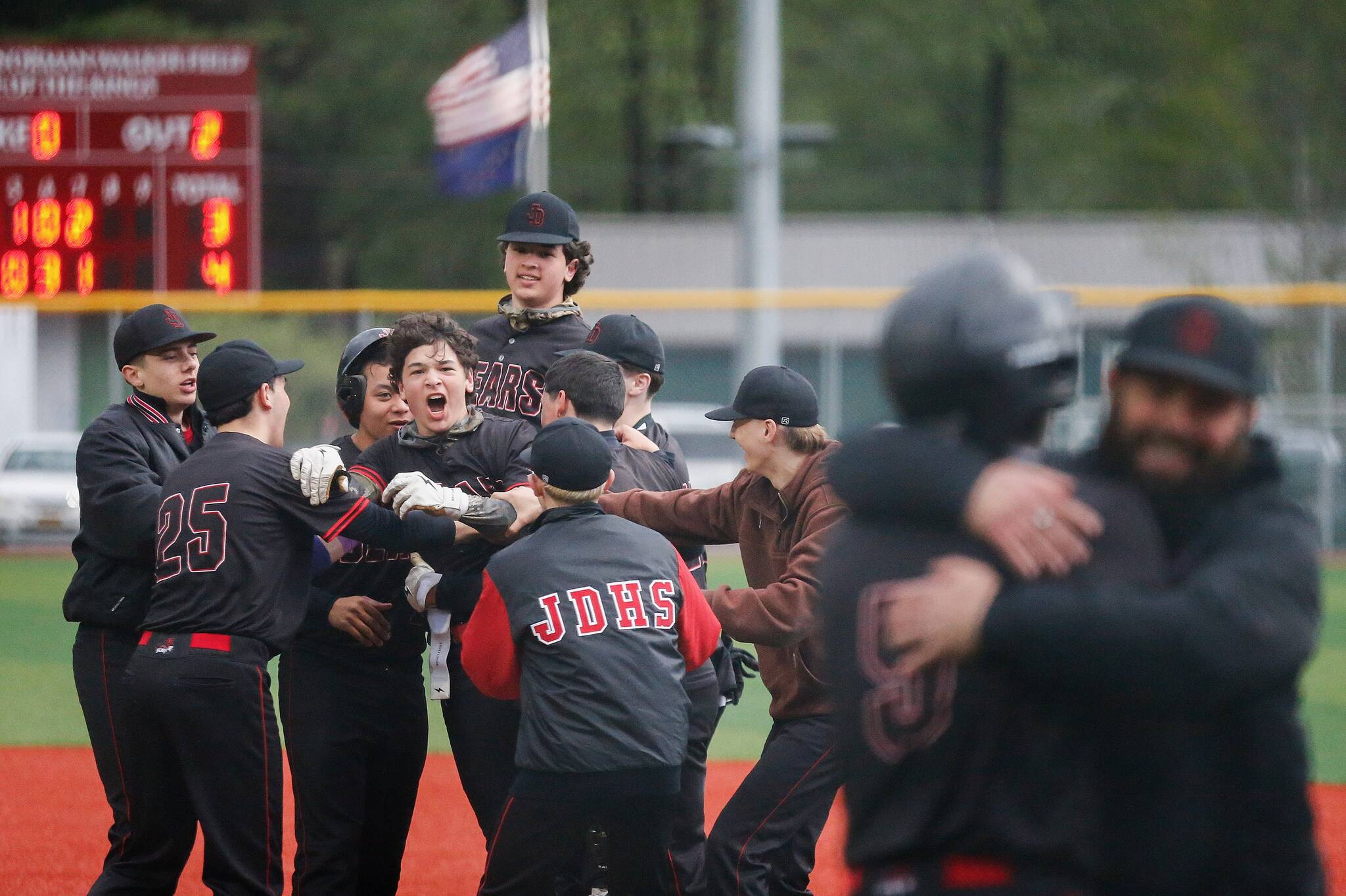 Juneau-Douglas High School: Yadaa.at Kalés Nate Fick is mobbed by team members after hitting a walk-off RBI single to give Juneau Douglas a 4-3 victory over Ketchikan on the second day of the Region V Baseball tournament at Norman Walker Field on Friday, May 30, 2025. (Christopher Mullen/Ketchikan Daily News)
