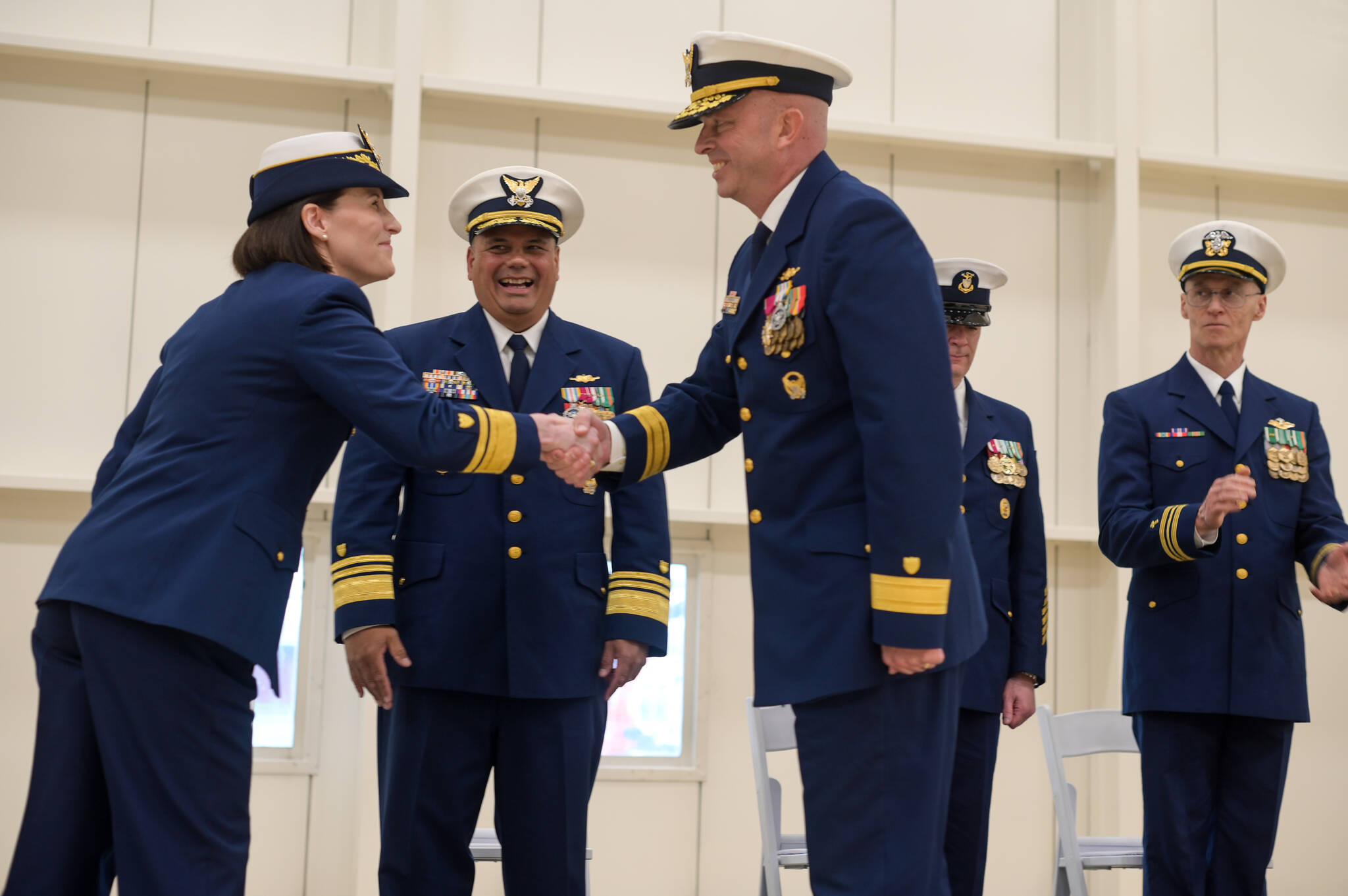 U.S. Coast Guard Rear Admiral Megan Dean shakes hands with the new Arctic District commander Rear Admiral Bob Little on Friday, July 11. Vice Admiral Andrew J. Tiongson, Commander of the Pacific Area, smiles. (Jasz Garrett / Juneau Empire)