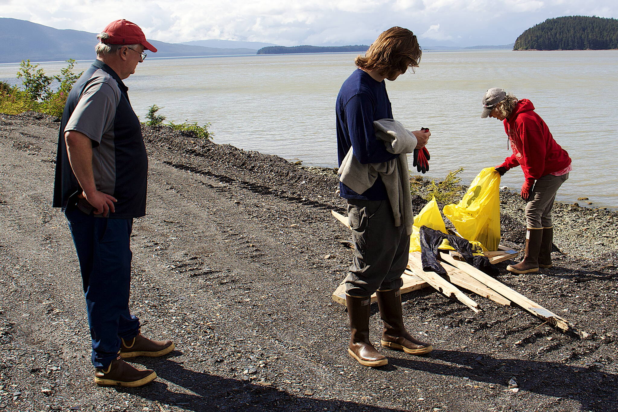 Hal Kulm (left), Luke Kulm (center) and Chanda Lawless place trash and lumber debris by the side of North Douglas Highway during a community shoreline cleanup. (Mark Sabbatini / Juneau Empire file)