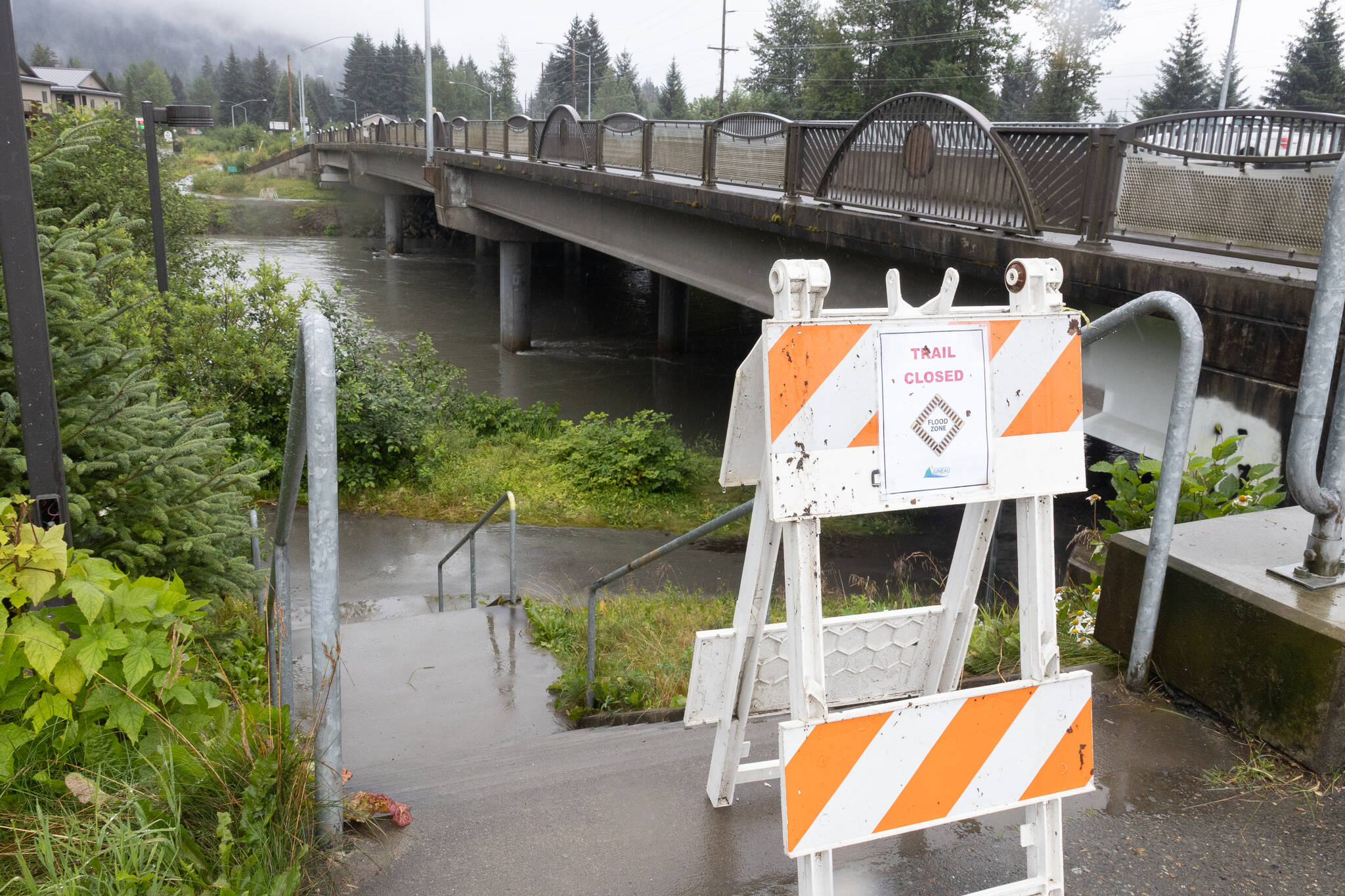 A sign warning of flood risk is posted by Brotherhood Bridge on Aug. 11, 2025. (Chloe Anderson for the Juneau Empire)