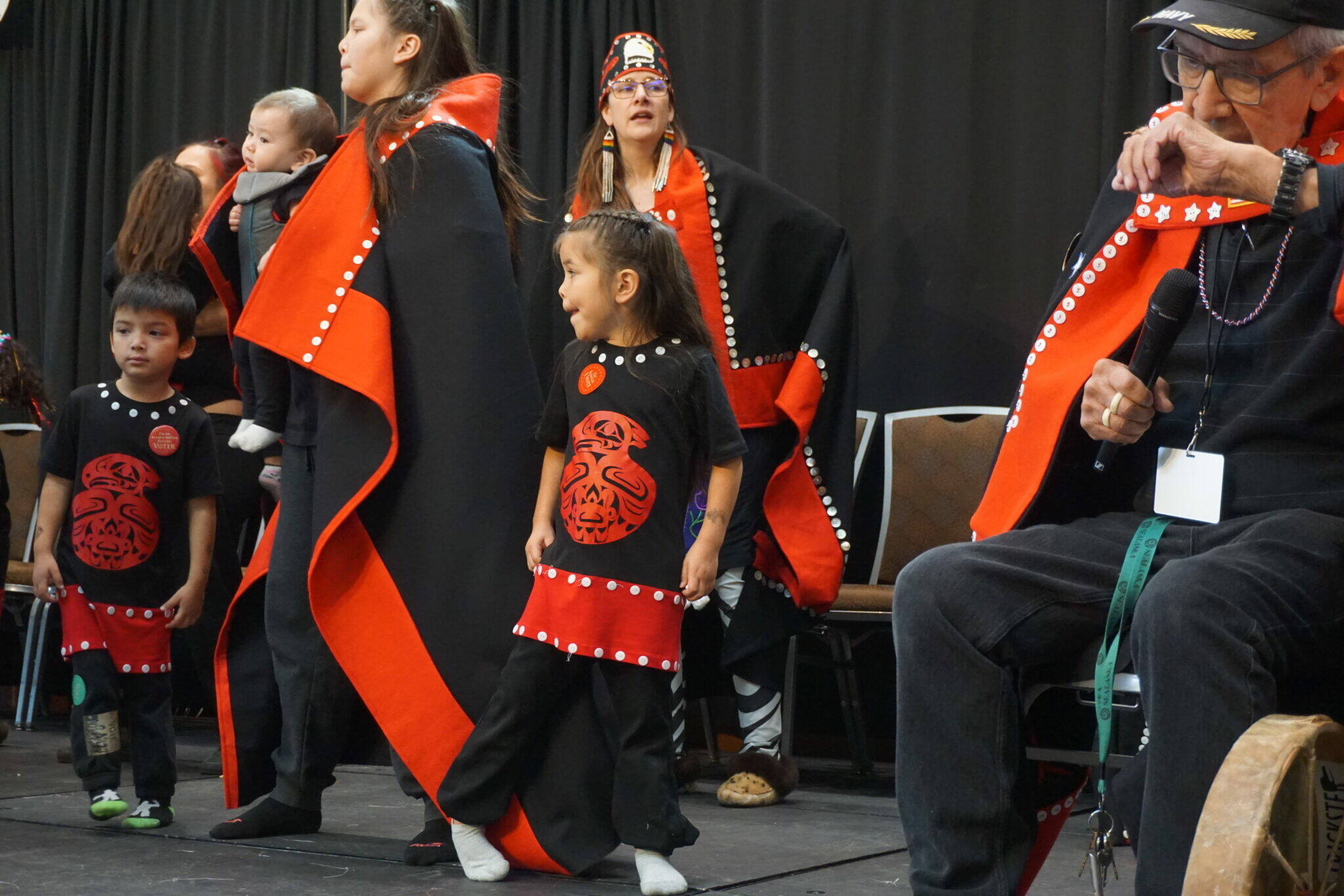 Photo by Yereth Rosen/Alaska Beacon
Members of the Tlingit, Haida and Tsimshian group Aanchich’x Kwaan perform on Oct. 18, 2025, at the Alaska Federation of Natives convention in Anchorage. The dance and singing group has members of all age groups, from young children to elders. The group was among several that performed traditional dances at the convention.