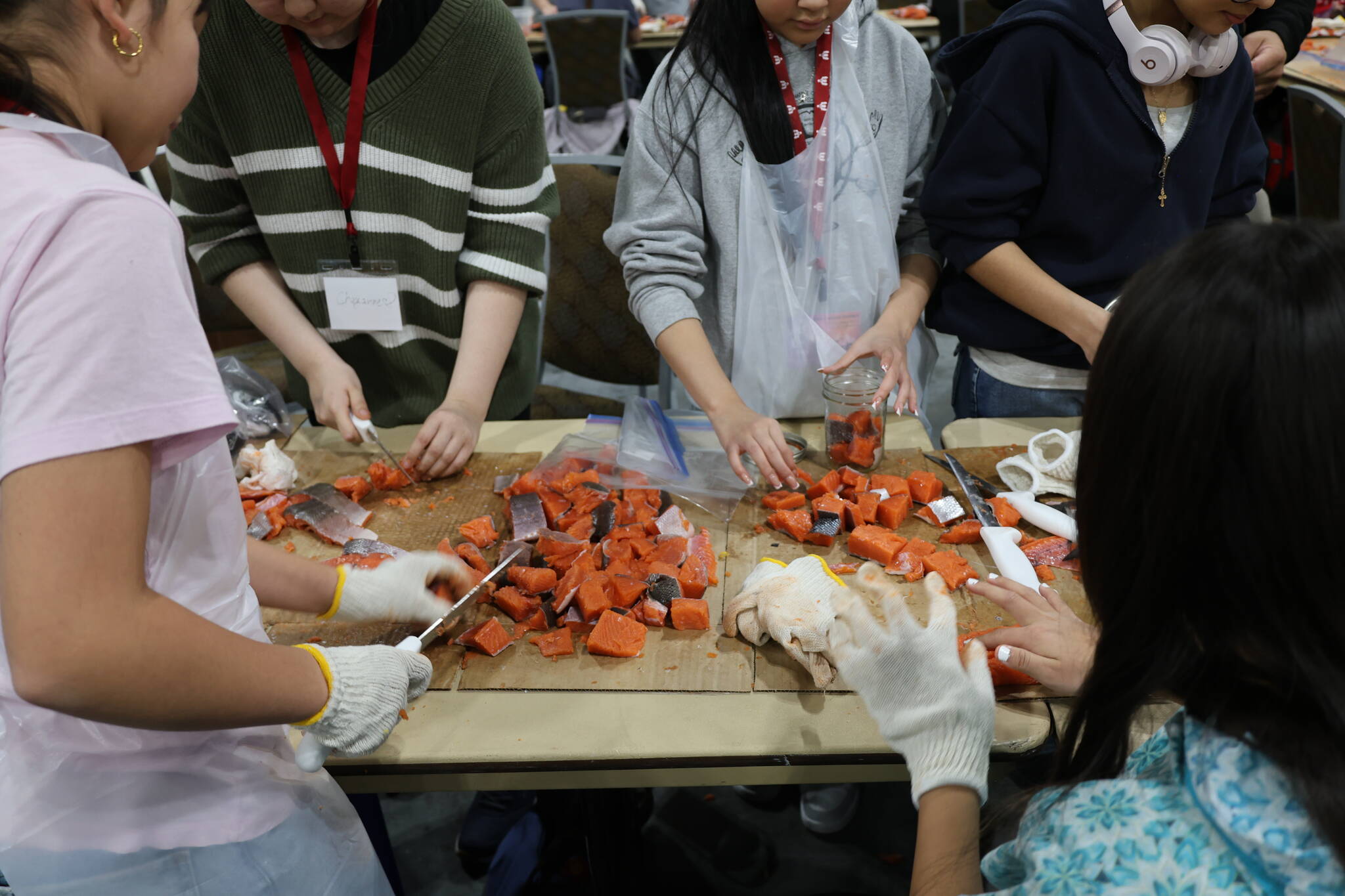 Young people cutting salmon at the First Alaskans Institute Elders & Youth Conference, which took place in Anchorage from Oct. 12-15. (Photo courtesy of Aaron Angerman).
