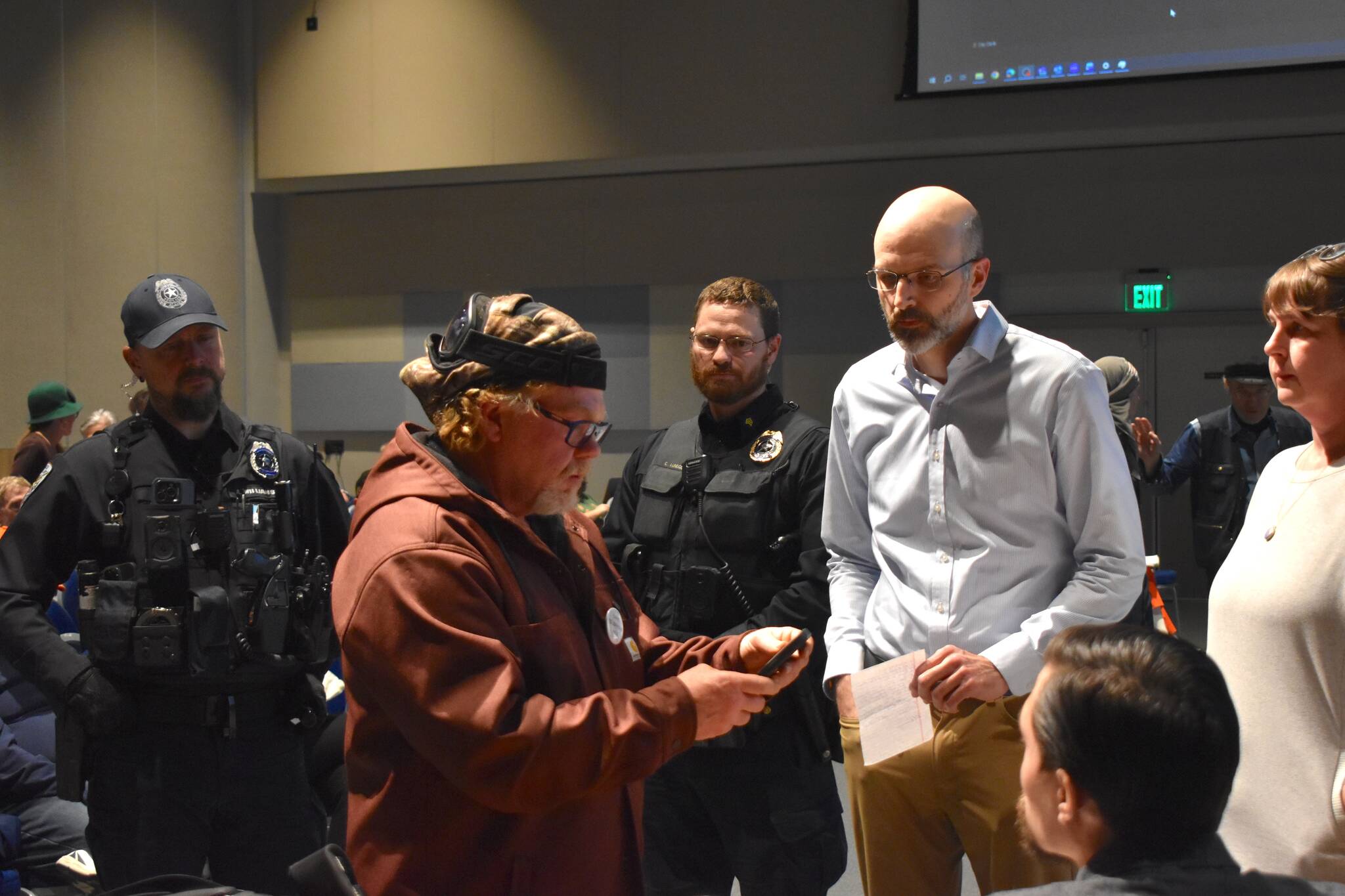 Deputy City Manager Robert Barr, right, hands KC Kreger, left, a trespass letter asking him to leave the Assembly meeting on Monday, Oct. 27. (Mari Kanagy/Juneau Empire