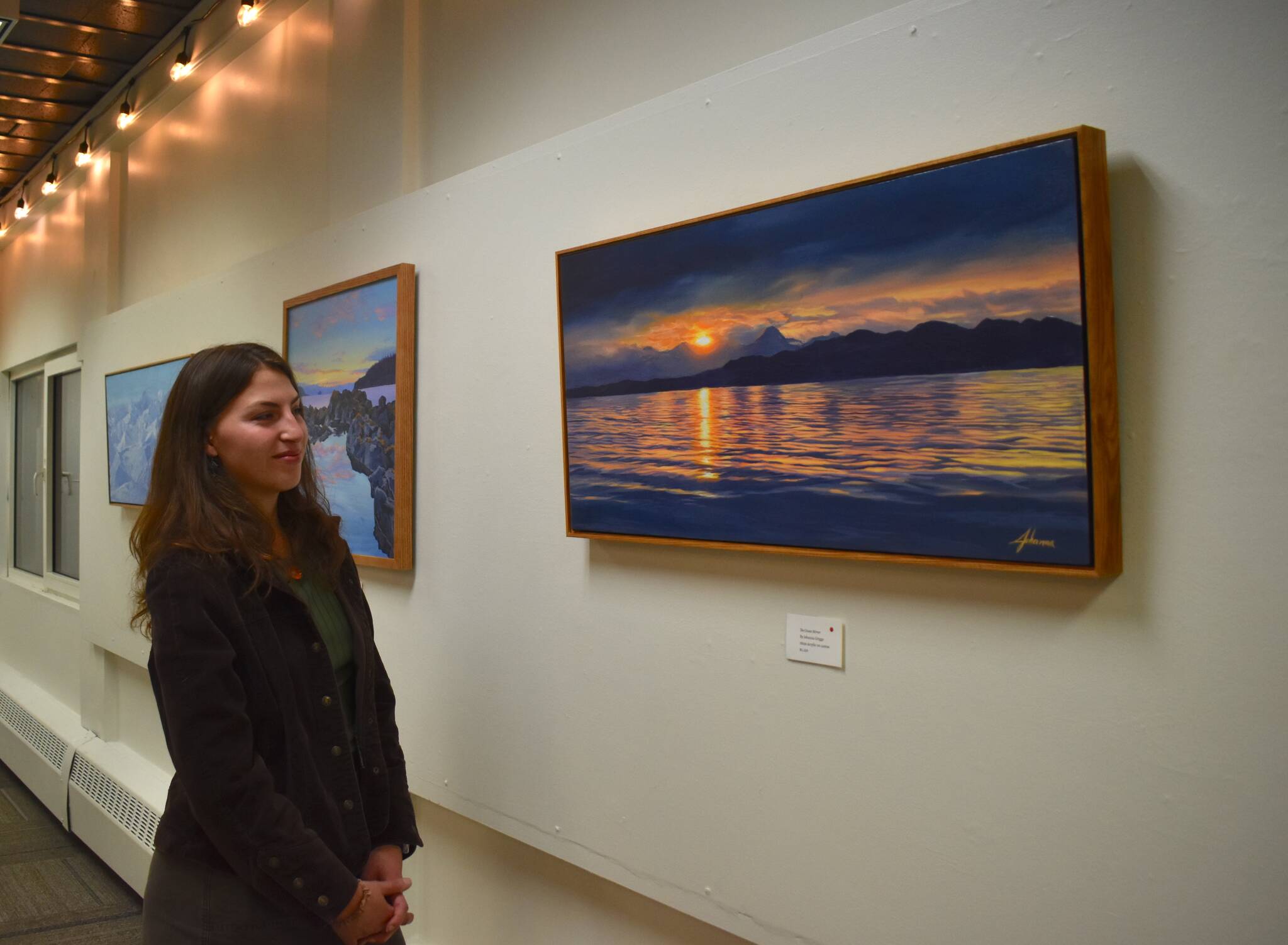 Local artist Johanna Griggs looks at The Ocean Mirror, her favorite piece from her exhibit Landscapes of Southeast Alaska, on display at the Juneau Arts and Culture Center. (Mari Kanagy/Juneau Empire)