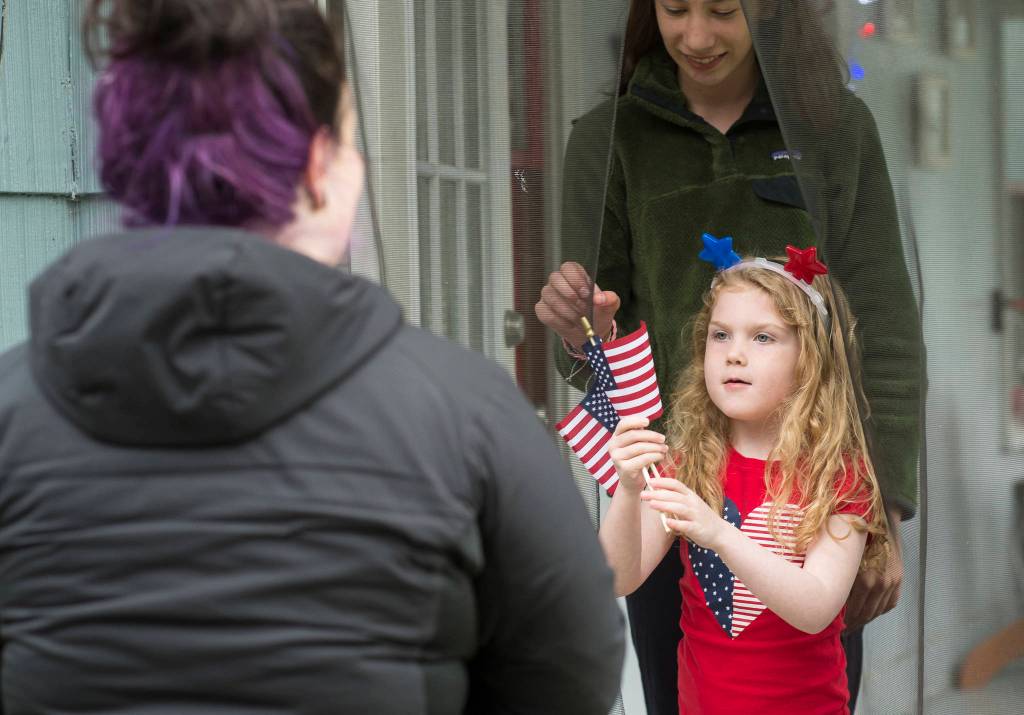 Capital City Fire/Rescue Volunteer Firefighters Antonia Elstad hands out flags to Anna Begenyi, 6, and Kiera Liska during a tour of Douglas properties to judge on Flag Day, Thursday, June 14, 2018. (Michael Penn | Juneau Empire)