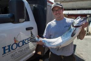 Brad Robbins, the new owner of the Hooked Seafood Company, holds a fresh king salmon at their Industrial Boulevard location on Tuesday, June 19, 2018. (Michael Penn | Juneau Empire)