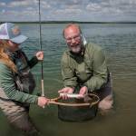 Abbey Whitcomb and her client, Naknek resident Bryon Singly, pose with a small rainbow on the Naknek River. (Courtesy Photo | Sarah Miller)