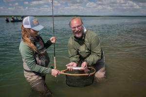 Abbey Whitcomb and her client, Naknek resident Bryon Singly, pose with a small rainbow on the Naknek River. (Courtesy Photo | Sarah Miller)