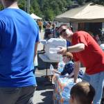 Jim Carter, pastor at the Northland Bible Church in Juneau, hands out free water bottles to passersby at Savikko Park on July 4, 2018. (Kevin Gullufsen | Juneau Empire)