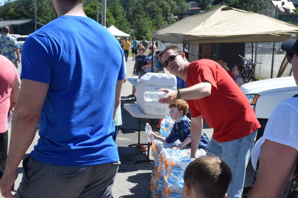 Jim Carter, pastor at the Northland Bible Church in Juneau, hands out free water bottles to passersby at Savikko Park on July 4, 2018. (Kevin Gullufsen | Juneau Empire)