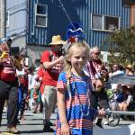 A girl carries a banner for the Juneau Volunteer Marching Band in the Douglas Fourth of July parade Wednesday. (Kevin Gullufsen | Juneau Empire)