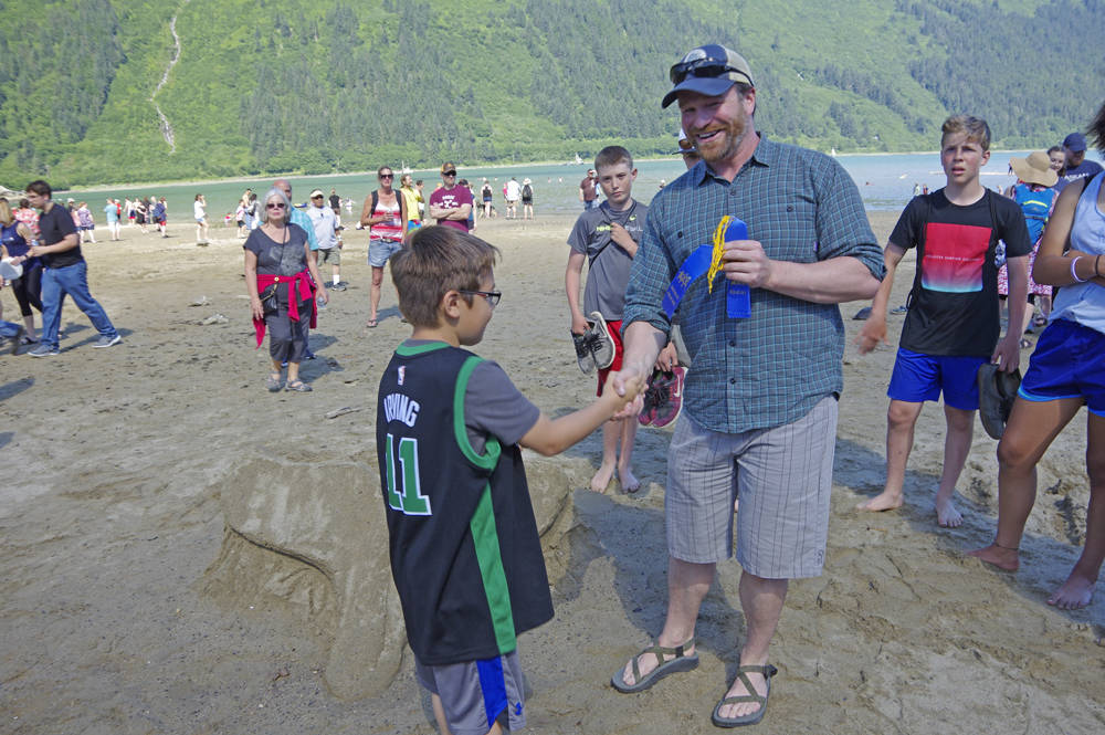 Zane Jones, chair of the Southeast Alaska Section of the American Insititute of Architects, awards a young participant in the Douglas Sandcastle Challenge. (Photo courtesy Zane Jones)