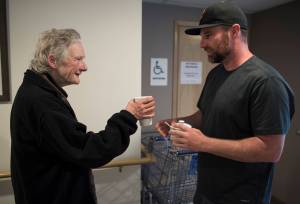 Trevor Kellar, a community navigator for St. Vincent de Paul, offers Sheila Robinson a cup of coffee on Friday, July 20, 2018. (Michael Penn | Juneau Empire)