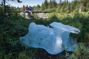 With an iceberg grounded in front of them, Kelly Mercer and her father, Fred Gerle, relax on a bench at the Mendenhall Campground on Friday, July 20, 2018, after Thursdays flood of Mendenhall Lake. (Michael Penn | Juneau Empire)