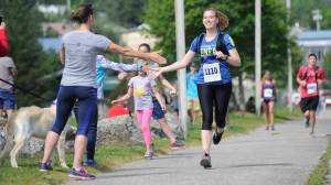Nicole Gorle, 27, high fives a spectator while finishing the Juneau Half Marathon on Saturday at Savikko Park. (Nolin Ainsworth | Juneau Empire)
