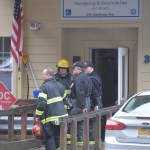 Firemen wait outside the entrance of the Channel View Apartments on Sunday afternoon. A fire broke out in a unit on the fifth floor.