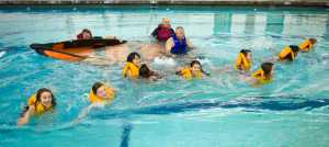Third grade girls from Harborview Elementary School swim from a sinking boat as they learn water safety at the Augustus Brown Public Swimming Pool on Friday. Helping teach are Coast Guard Auxiliary members Mark Hunt, left, and Stu Robards, center, and current Coast Guard Chief Chief Warrant Officer Rick Nieves.
