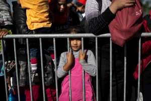 A girl stands behind a barrier as people queue to get into a reception center for migrants and refugees in Opatovac, Croatia, Wednesday.
