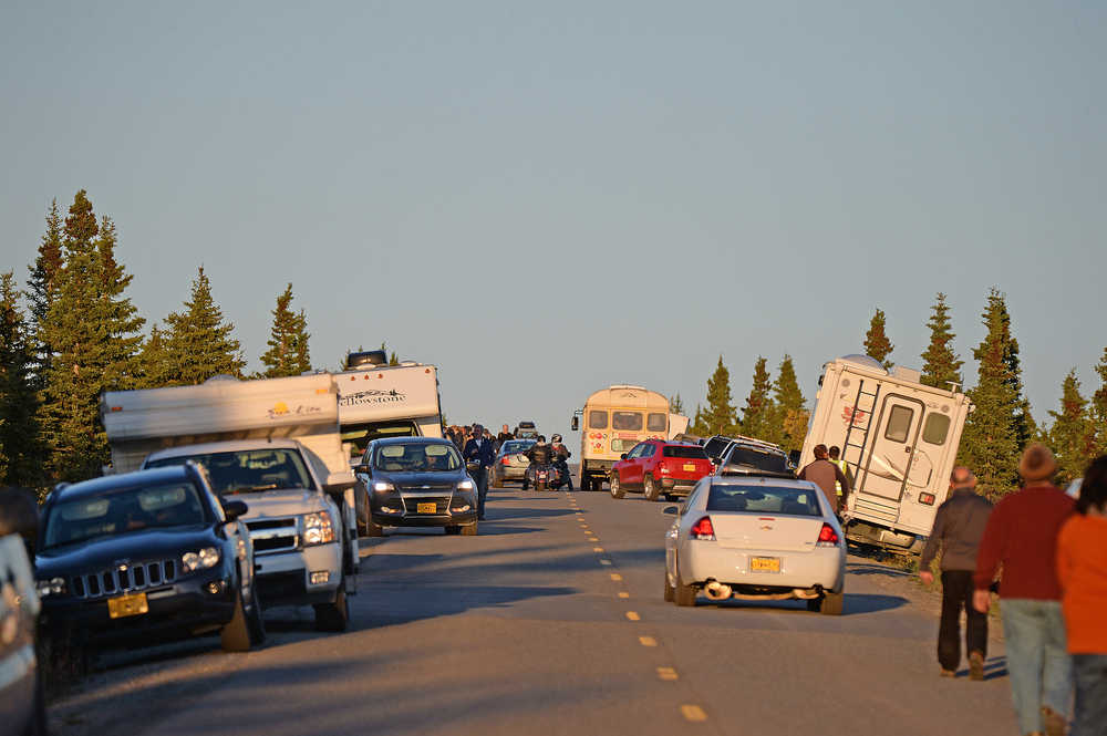 A "Bear jam" at Denali National Park and Preserve. Cars, campers and buses line both lanes of the highway and photographers gather to photograph a wild animal.