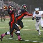 Juneau-Douglas senior Kana Galletes (51) blocks after a snap during high school football action this season as quarterback Bubba Shults passes.
