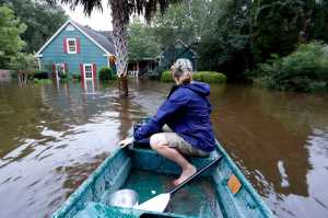 Jeanni Adame rides in her boat as she checks on neighbors Tara Saracina seeing if she wants to evacuate  in the Ashborough subdivision near Summerville, S.C., after many of their neighbors left Monday, Oct. 5, 2015. South Carolina is still struggling with flood waters due to a slow moving storm system. (AP Photo/Mic Smith)