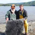 Jim Baichtal, left, and Ian Putnam, right, pose with the largest part of the palm leaf fossil they unearthed near Kake. They estimate it's between 50 and 50 million years old.