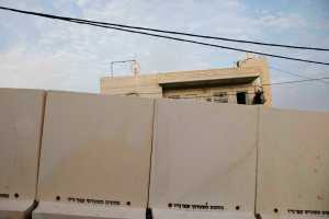A Palestinian man stands on his balcony Sunday as he looks at concrete barrier between the Arab neighborhood of Jabal Mukaber and the Jewish area of Armon Hanatziv in east Jerusalem. I