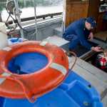 Jacob Miller shows U.S. Coast Guard First Class Ben Stixrud his safety gear on his 41-foot power troller at the Don Statter Memorial Boat Harbor in Auke Bay on Friday.