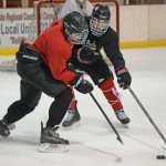 JDHS freshman Bill Bosse and junior Niko Hebert work for a puck during Wednesday morning practice at Treadwell Arena.