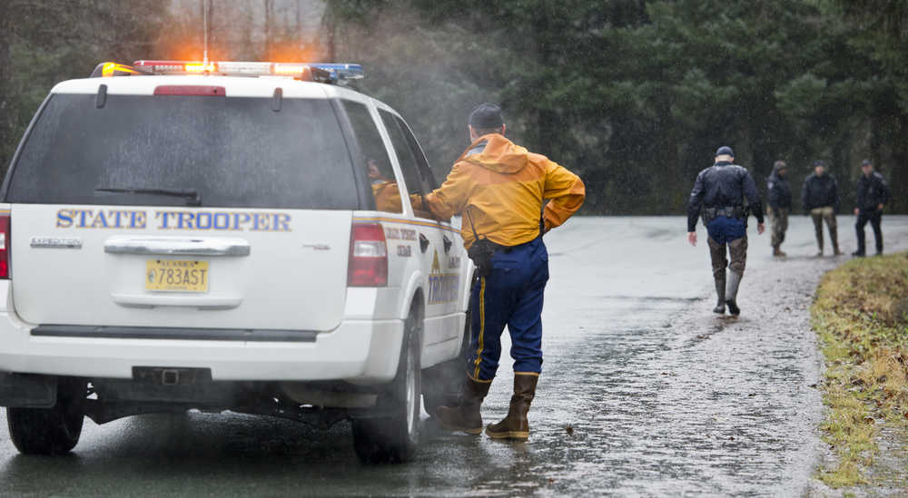 Alaska State Troopers help Juneau Police Department detectives search the woods near the Kodzoff Acres Mobile Home Park on Thursday.