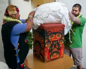 Tlingit Tribe members from Klawock, Alaska Jonathan Rowan, left, and Lawrence Armour unveil a carved Alaskan storage box at the Honolulu Museum of Arts, Thursday, Oct. 22, 2015, in Honolulu.   A totem pole, stolen by actor John Barrymore during a sailing trip to Alaska in 1931, was returned to the Tlingit Tribe by the Honolulu Museum of Arts today, where it was on display since the early 1980s.  The totem pole was carved by the ancestors of the Tlingit Tribe.  The box was a thank you gift for the return of their totem pole.  (AP Photo/Marco Garcia)