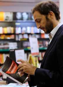 Italian journalist Emiliano Fittipaldi browses through his book titled " Avarice" in a Rome's bookstore on Tuesday.