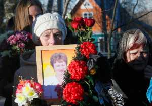 A woman holds a portrait of Nina Lushchenko, one of the victims of a plane crash,  during her funeral at a cemetery in the village of Sitnya, 80 km (about 50 miles) of Veliky Novgorod, Russia, Thursday, Nov. 5, 2015.  The first victim of Saturday's plane crash in Egypt was laid to rest on Thursday following a funeral service in a medieval church in the north Russian city of Veliky Novgorod.  Russia's Airbus 321-200 broke up over the Sinai Peninsula en route from the resort town of Sharm el-Sheikh to St. Petersburg, killing all 224 on board. (AP Photo/Dmitry Lovetsky)