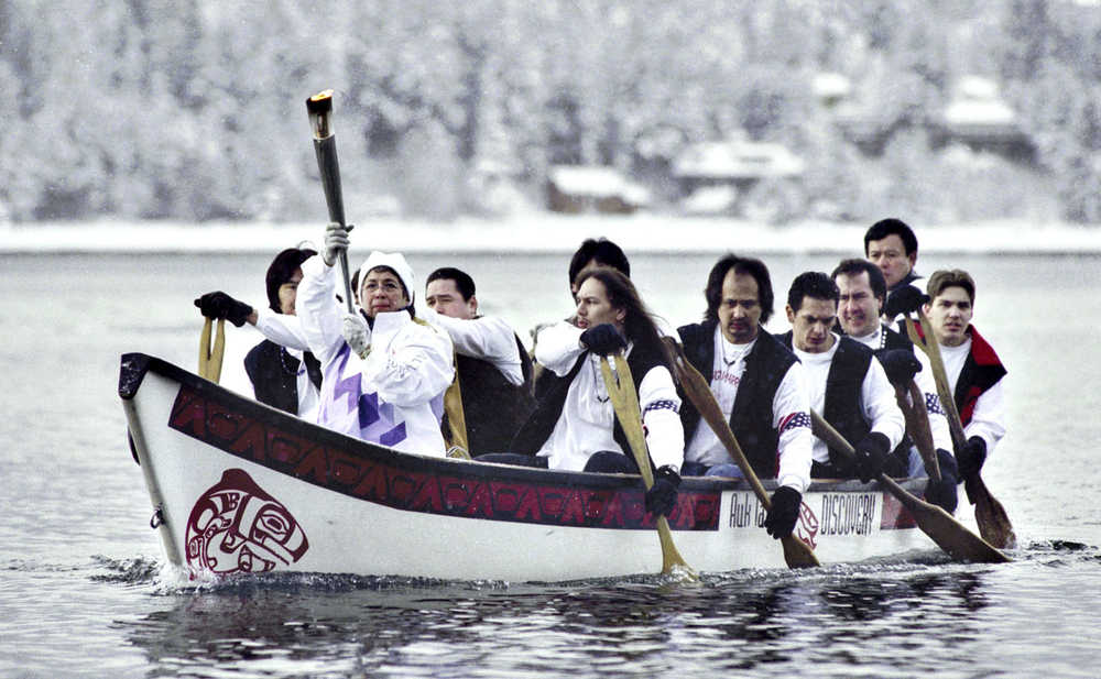 Ethel Lund holds the Olympic flame high as members of a Tlingit canoe team paddle across Juneau's harbor toward the Intermediate Vessel Float during the 2002 Olympic Torch Relay in January, 2002.