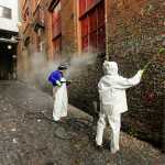 Fernando Soberania, left, and Javier Ramirez, right, work to clean layers of gum from Seattle's famous "gum wall" at Pike Place Market Tuesday.