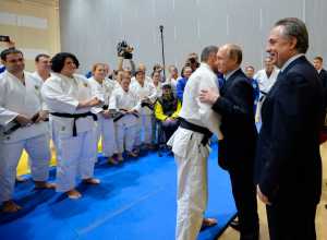 Russian President Vladimir Putin, second right, embraces with an athlete as Sports Minister Vitaly Mutko, right, smiles during a visit to the federal government center "South Sports" before their late-night meeting with the heads of Russia's sports federations in the Black Sea resort of Sochi, Russia, on Wednesday. (Alexei Druzhinin | RIA-Novosti, Kremlin Pool Photo via AP)