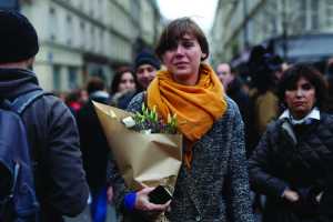 A woman carrying flowers cries in front of the Carillon cafe and the Petit Cambodge restaurant Saturday in Paris.
