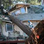 In this Nov. 21, 2015 photo, Jake Hines, left, and Ross Rukke, of Capstone Construction, work to remove a fallen tree in Spokane, Wash., after deadly storms swept through the state leaving many without power.  (Dan Pelle/The Spokesman-Review, via AP)