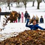 Fourth-grader Remi Starks, left, tosses an armful of leaves as fifth-grader Kayla Woodbury takes her turn jumping into a pile of dried leaves at Evergreen Cemetery on Tuesday.