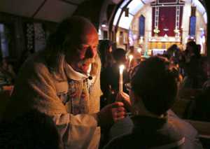 In this Nov. 18 photo, the Rev. Scott Fisher hands a Baptism candle to Aiden Taylor during a service at St. Matthew's Episcopal Church in Fairbanks.