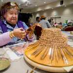 Percy Kunz works with red and yellow cedar bark to make a childs hat at the Native Artists Market in the Elizabeth Peratrovich Hall on Friday.