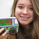 Eighth-grader Isabelle Wassilie shows off her car design in teacher Alan Denerger's technology class at Floyd Dryden Middle School on Thursday. Students can design the wooden CO2 powered-cars to be fast or just fun.