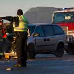 A Capital City Fire/Rescue firefighter attends to a two-vehicle accident as a Juneau police office directs traffic on Egan Drive at Vanderbilt Hill Road Friday morning.