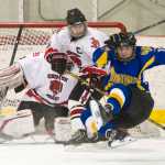 Monroe Catholic's Grant Olson, right, trips in front of Juneau-Douglas'  Chase Barnum and goalie Kyle Farley-Robinson at Treadwell Arena on Saturday. Monroe Catholic won 3-1.