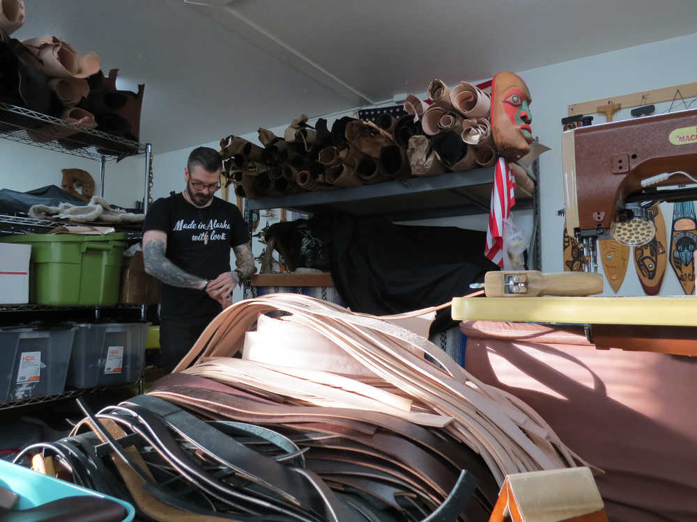 Dan Ewing in his shop and studio, a storage unit in Lemon Creek. In the foreground are some strips of leather he's cut for custom-made belts.