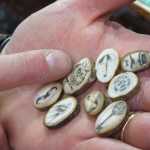 Dan Ewing of Ewing Dry Goods holds some cut walrus teeth with scrimshaw designs done by Milo Irish, an artist at High Tide Tattoo.