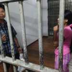 In this Friday, Nov. 13, 2015 photo, Burmese shrimp shed worker Tin Nyo Win, left, and his wife, Mi San, stand in a jail cell after they were arrested in Samut Sakhon, Thailand. Even after Tin Nyo Win became a whistleblower against the shrimp shed where they worked, the couple was fingerprinted and held on nearly $4,000 bail and charged with entering the country illegally and working without permits. (AP Photo/Robin McDowell)