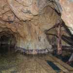 Inside the Mill Adit, with a dark water-filled shaft on the right.