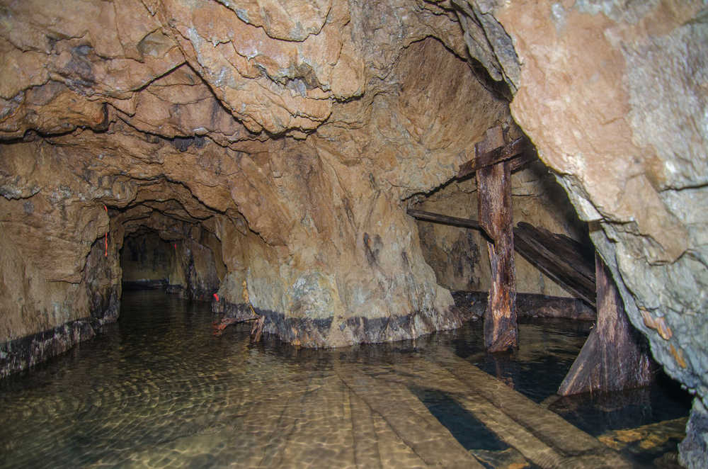 Inside the Mill Adit, with a dark water-filled shaft on the right.